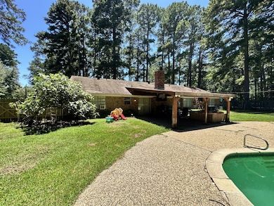 Rear view of house with a chimney, a patio, brick siding, and roof with shingles