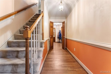 Hallway with wood finished floors, stairs, baseboa