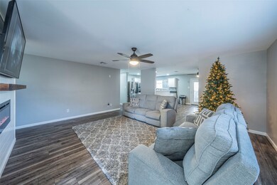 Living area featuring dark wood-type flooring, a ceiling fan, and a fireplace