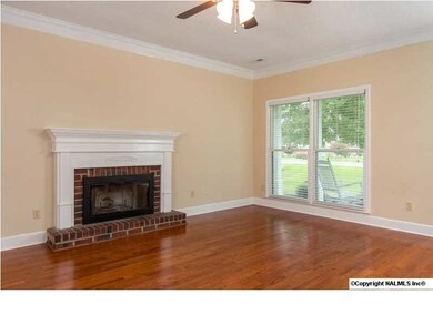 The family room is at the heart of the home and shows off new hardwood flooring. Snuggle up to the heat offered by a wood-burning fireplace. A ceiling fan, crown molding and plantation-style blinds finish off the room.
