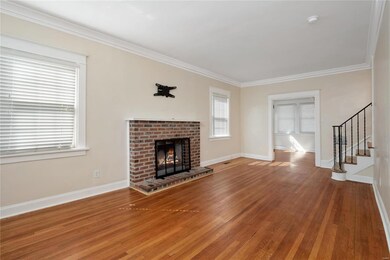 Living room with wood flooring, wood burning fireplace adjacent to sitting room with French doors