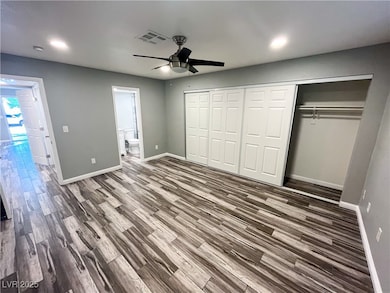 Unfurnished bedroom with a ceiling fan, dark wood-style flooring, a closet, and ensuite bathroom