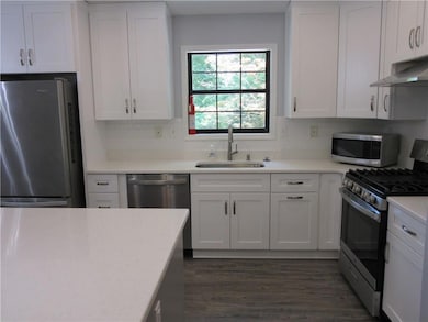 Kitchen with appliances with stainless steel finishes, light countertops, decorative backsplash, and white cabinetry