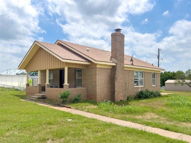 View of front of home with brick siding, a chimney, a shingled roof, and a front lawn