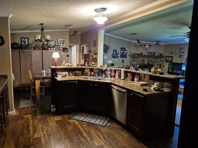 Kitchen with a textured ceiling, crown molding, dark cabinets, lofted ceiling, and dark wood-type flooring