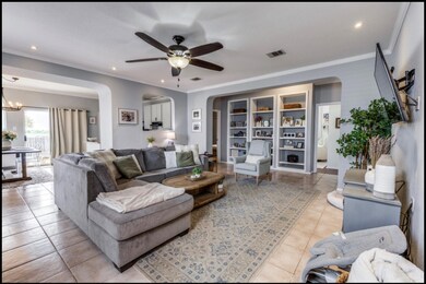 Living room with arched walkways, crown molding, recessed lighting, light tile patterned floors, and ceiling fan