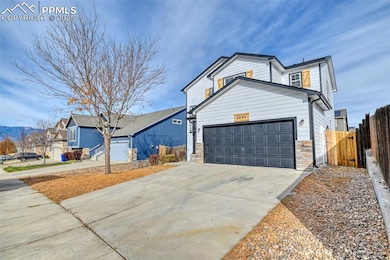 View of front facade featuring a garage, concrete driveway, and stone siding