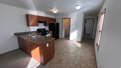 Kitchen with black appliances, dark countertops, independent washer and dryer, a peninsula, and under cabinet range hood