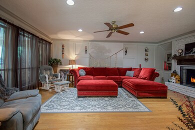 Spacious living/family room features a gas fireplace, ceiling fan & view of the sunroom/backyard.