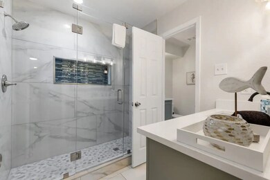 Bathroom with a marble finish shower, vanity, and light tile patterned flooring