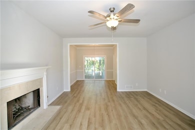 living room featuring  wood-style flooring, a fireplace, a chandelier, and a ceiling fan