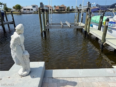 Dock area with boat lift, a water view, and a resi