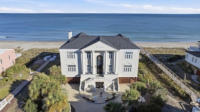 View of front facade with view of water and beach, stucco siding, stairway, and driveway