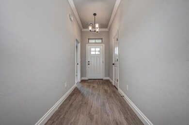 Entryway with ornamental molding, wood finished floors, and a chandelier