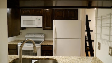 Kitchen featuring dark brown cabinetry, granite co