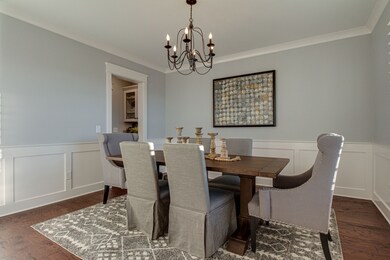 The formal dining room has large windows, a chandelier and wainscoting. A butler's pantry connects the dining room to the kitchen.