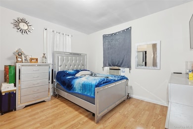 Bedroom featuring baseboards, light wood-style flooring, and cooling unit