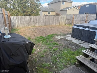Fenced backyard featuring a hot tub