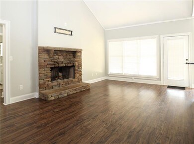 Unfurnished living room featuring a fireplace, dark wood-type flooring, ornamental molding, and high vaulted ceiling