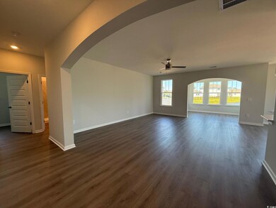 Unfurnished living room with a ceiling fan, arched walkways, dark wood finished floors, baseboards, and recessed lighting