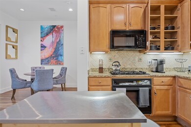 Kitchen featuring black appliances, crown molding, wood finished floors, backsplash, and a center island