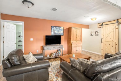 Living area with a barn door and wood finished floors