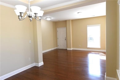 Unfurnished room with a chandelier, dark wood-type