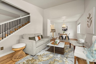 Living area with wood finished floors, stairway, and a chandelier