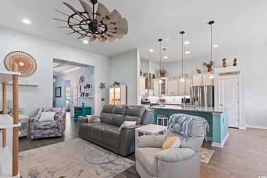 Living room with ceiling fan, sink, and dark wood-