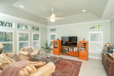 Living area with a tray ceiling, a ceiling fan, light wood-style floors, recessed lighting, and ornamental molding