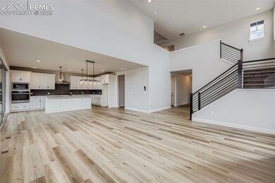 Unfurnished living room featuring recessed lighting, light wood-type flooring, a towering ceiling, and stairway