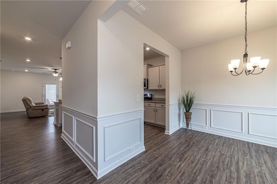 Unfurnished dining area featuring dark wood-style floors, a chandelier, recessed lighting, wainscoting, and a decorative wall