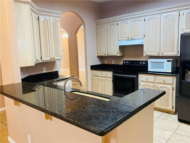 Kitchen featuring light tile patterned flooring, black appliances, under cabinet range hood, a peninsula, and arched walkways