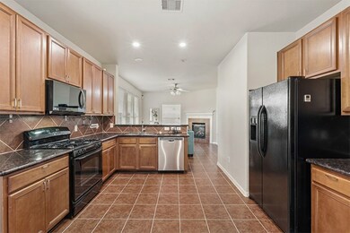 Spacious kitchen with wood cabinetry, granite counters, and gas range.