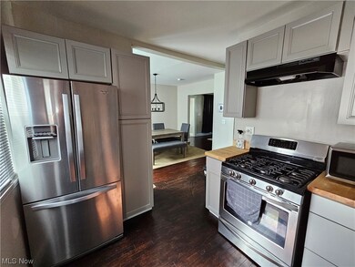 Kitchen featuring white cabinets, stainless steel appliances, light countertops, and dark hardwood flooring. Appliances not included