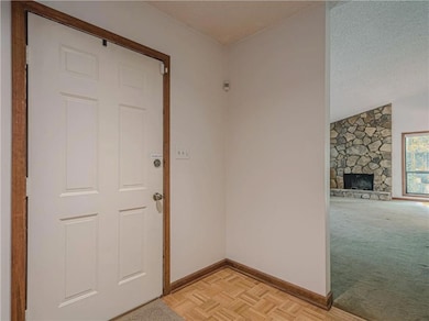 Foyer with peek of Greatroom including a fireplace, and light carpet