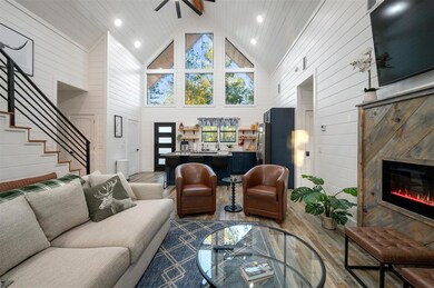 Living room featuring hardwood / wood-style flooring, wooden walls, and high vaulted ceiling
