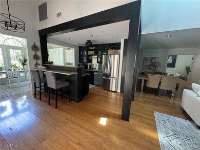 Kitchen featuring appliances with stainless steel finishes, light wood-style floors, a kitchen bar, a peninsula, and a high ceiling