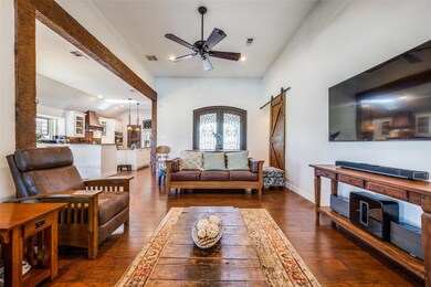 Living room featuring ceiling fan, plenty of natural light, dark wood-type flooring, and a barn door