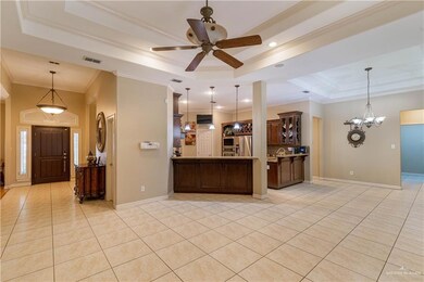 Kitchen with a raised ceiling, stainless steel fridge, crown molding, light tile patterned flooring, and a ceiling fan