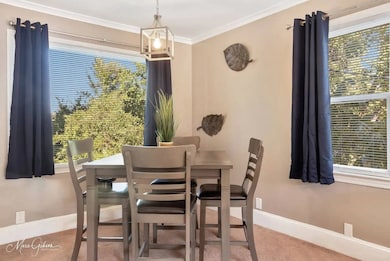 Dining area with light colored carpet and crown molding
