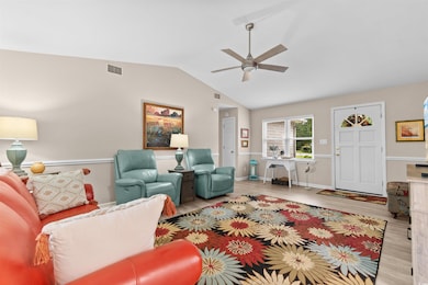 Living area featuring vaulted ceiling, wood finished floors, a ceiling fan, and a desk