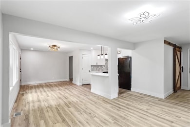 Unfurnished living room featuring a barn door, bas