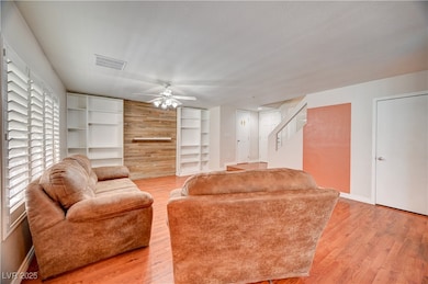 Living room featuring light wood-style floors, built in features, stairway, ceiling fan, and a textured ceiling