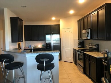 Kitchen with dark cabinetry, stainless steel appliances, a kitchen breakfast bar, light tile patterned floors, and backsplash