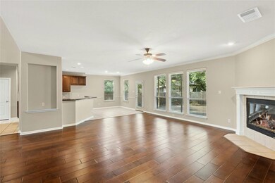 Unfurnished living room with ceiling fan, a tiled fireplace, crown molding, dark wood-type flooring, and baseboards