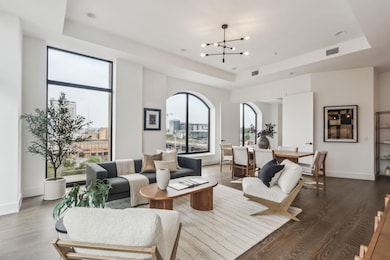 Living room featuring visible vents, a raised ceiling, and an inviting chandelier