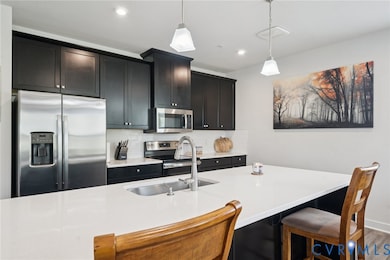 Kitchen with appliances with stainless steel finishes, tasteful backsplash, dark cabinetry, light stone counters, and recessed lighting