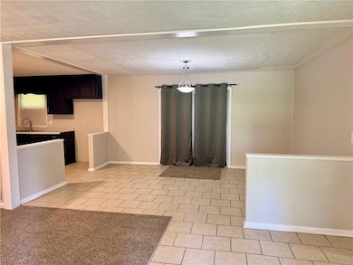 Unfurnished dining area with light tile patterned floors, a sink, and a textured ceiling