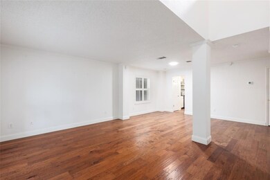 Unfurnished living room featuring dark wood finished floors, a textured ceiling, and decorative columns